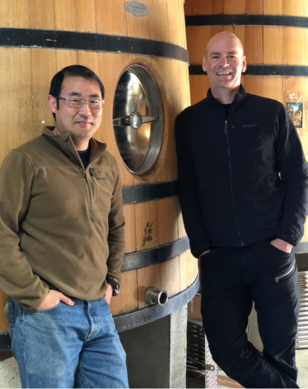 Kyle Mizuno and Aaron Pott infront of a wine barrel